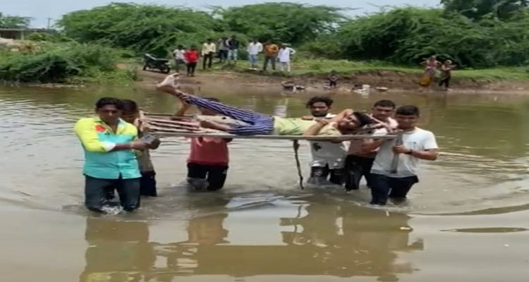 Untitled26593 તંત્રની બેદરકારીના અભાવે દર્દીને ખાટલામાં સુવડાવીને વહેતી નદીના પ્રવાહમાંથી પસાર થવા મજબુર ગ્રામજનો